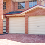 Double garage with closed roller doors and brick exterior, located in Prestons, New South Wales, Australia.