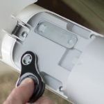 Hand adjusting the manual release lever on a white articulated arm automatic gate opener, suitable for use in Prestons, New South Wales, Australia