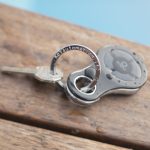 Black electronic key automation device with keys on keyring, resting on outdoor wooden bench in Prestons, New South Wales, Australia.
