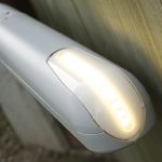 White articulated arm gate opener with illuminated LED indicator light, shown mounted on wood in Prestons, New South Wales, Australia.